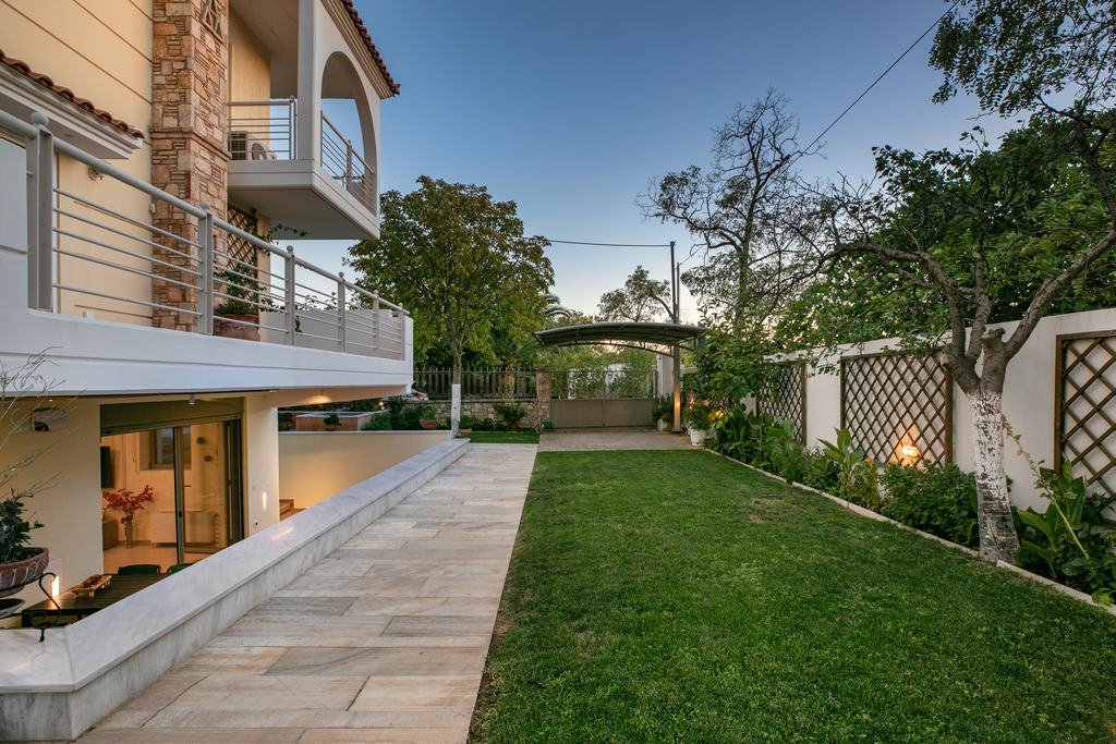 Marble path beside the lawn leading to the lit apartment at blue hour